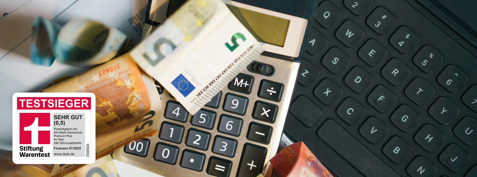 Ein Taschenrechner und Geldscheine liegen auf einer Tastatur. Zustäzlich ist die Stiftung Warentest Testsieger Auszeichnung zu sehen.