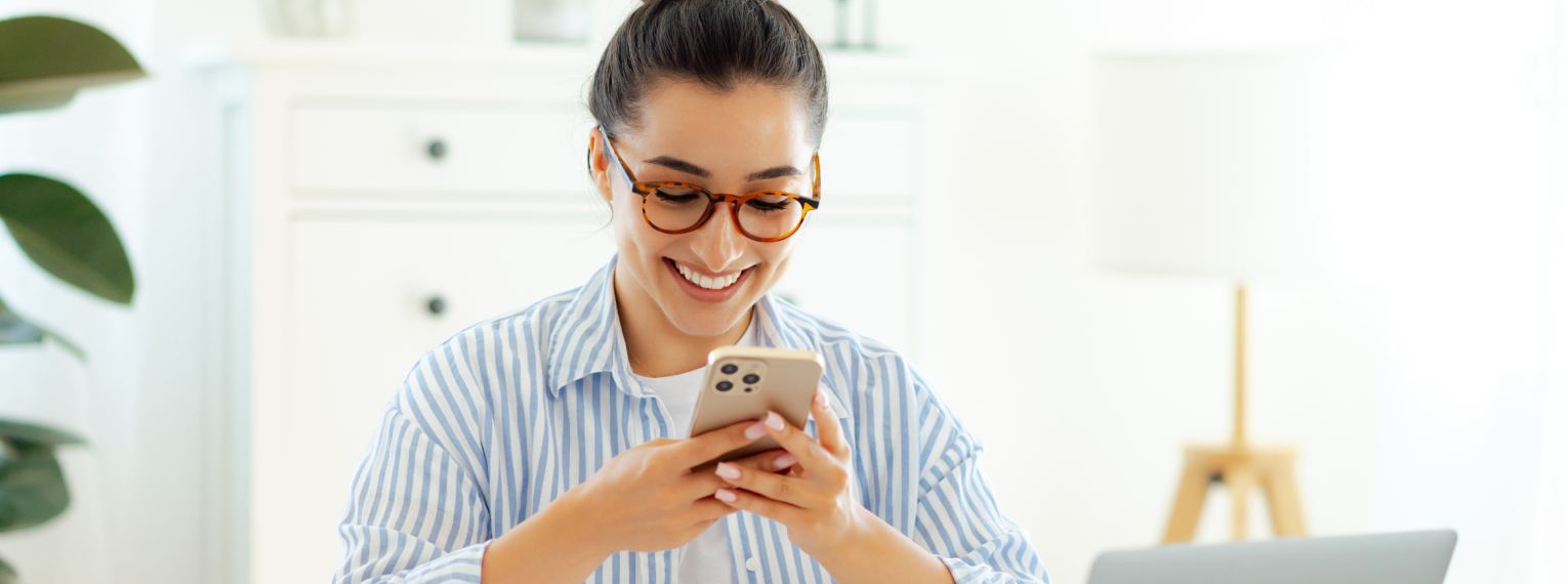 Eine Frau setzt am Handy ihre Zahnzusatzversicherung von der Steuer ab und lächelt dabei.