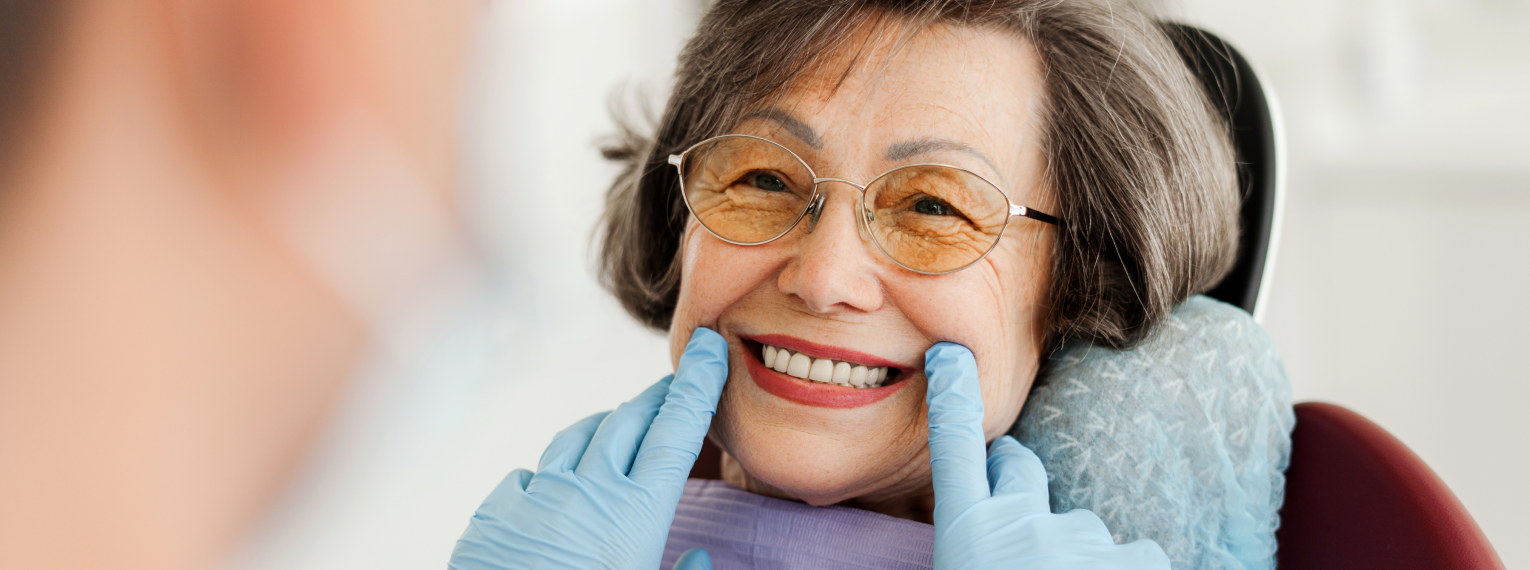 Eine Seniorin lächelt beim Zahnarzt.