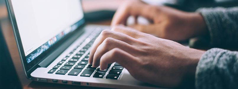 Tippende Hände auf Laptop-Tastatur auf der Suche nach der Frage: Welche ist die beste Zahnzusatzversicherung?