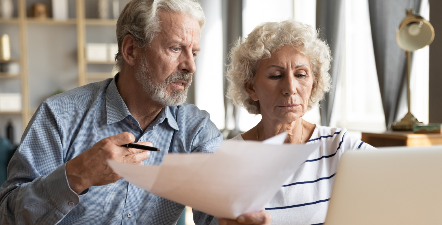 Ein älteres Paar vergleicht zwei Verträge für eine Zahnzusatzversicherung ohne Leistungsbegrenzung.